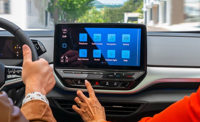 A close-up shot of a woman’s hand touching the ID.4 available 12" touchscreen display.