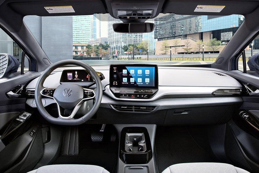 Interior shot of an ID.4 with focus on the front windshield, the dashboard, steering wheel, cup holder and center console display.