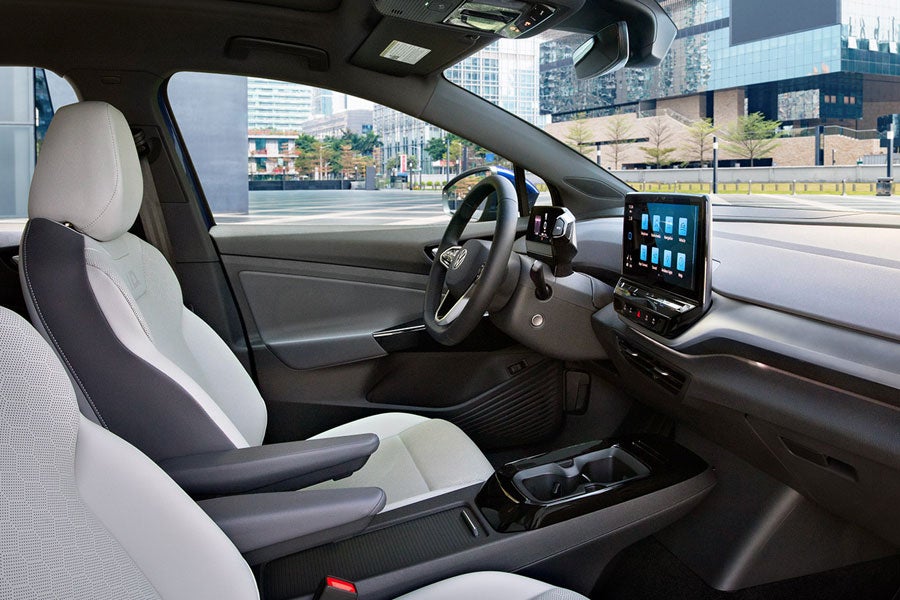 A shot of an ID.4 parked next to rock wall, with focus on the front seats, steering wheel, dash and center console display.