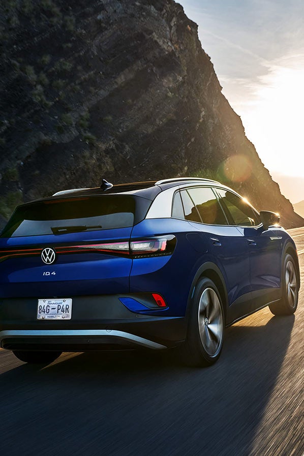A rear view of an ID.4 in Dusk Blue Metallic, driving along a mountain road.